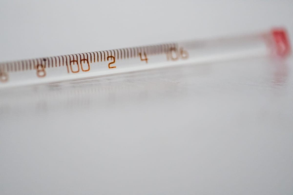 A glass thermometer photographed close up against a plain surface